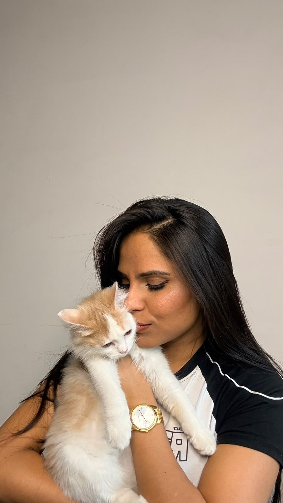 A pet parent kissing a cream kitten on the head