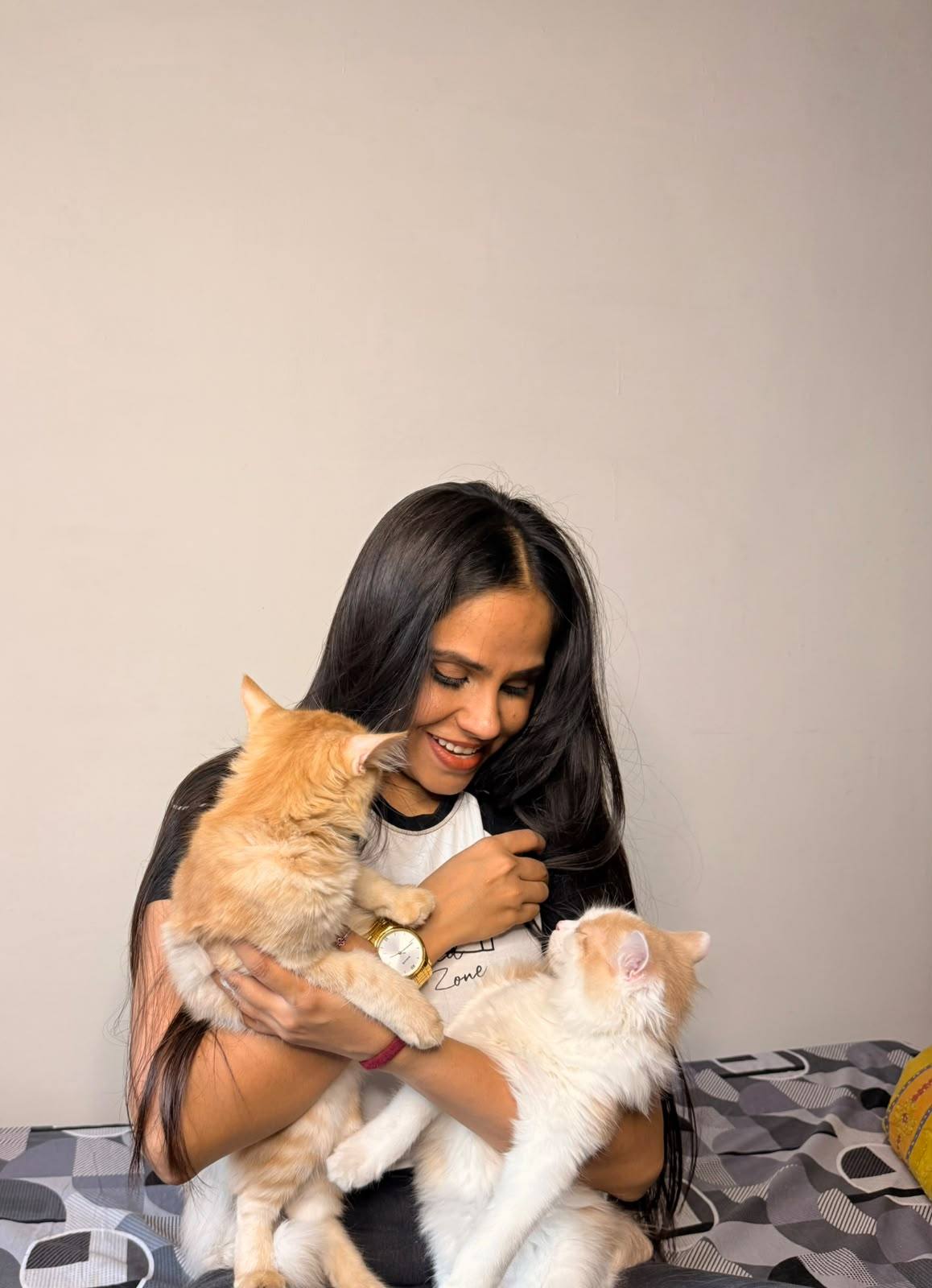 A pet parent cuddling two ginger cats on a bed